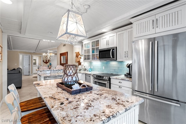 kitchen featuring pendant lighting, a kitchen island, decorative backsplash, appliances with stainless steel finishes, and white cabinets