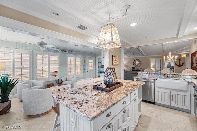 kitchen featuring decorative light fixtures, a center island, sink, a kitchen breakfast bar, and white cabinets