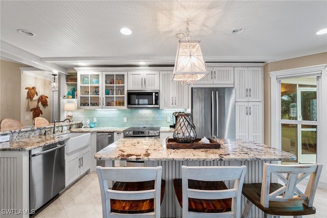 kitchen featuring a kitchen bar, light stone countertops, hanging light fixtures, and stainless steel appliances