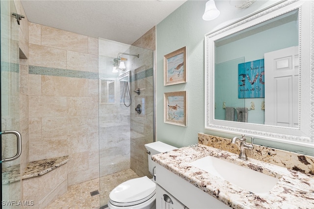 bathroom with toilet, a textured ceiling, walk in shower, and vanity