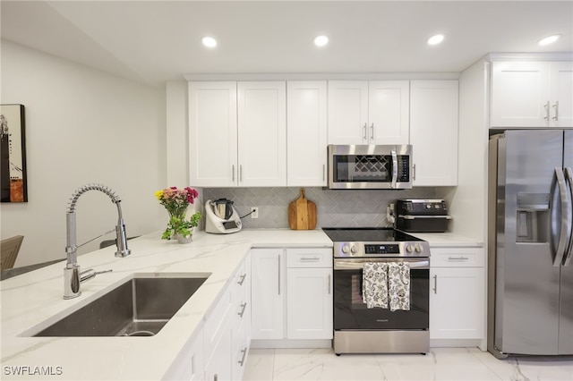 kitchen with stainless steel appliances, sink, white cabinets, light stone counters, and tasteful backsplash