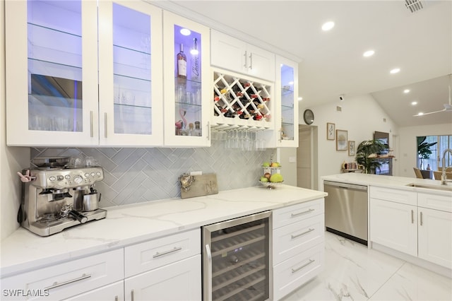 kitchen featuring beverage cooler, lofted ceiling, white cabinetry, stainless steel dishwasher, and backsplash