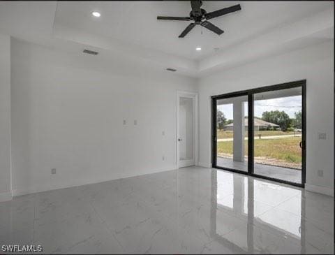 empty room featuring marble finish floor, a raised ceiling, a ceiling fan, and recessed lighting