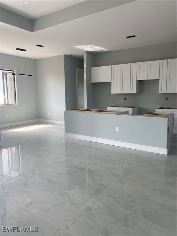 kitchen featuring open floor plan, baseboards, visible vents, and white cabinets