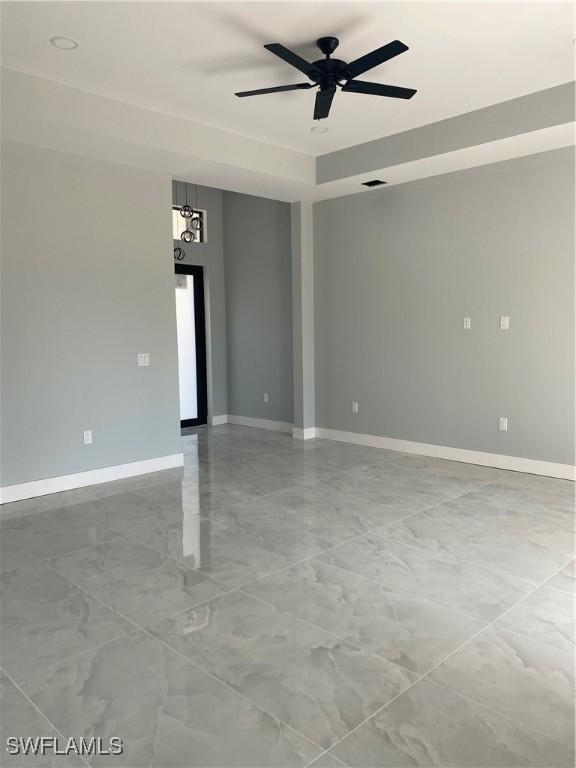 unfurnished room with marble finish floor, visible vents, ceiling fan, and baseboards