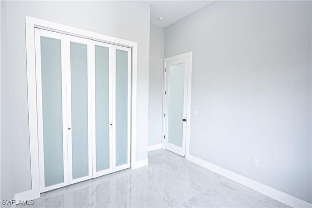 1254 Ellipse St E, Lehigh Acres, FL 33974 - unfurnished bedroom featuring baseboards, marble finish floor, and a closet