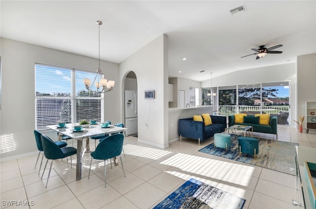 dining area featuring ceiling fan with notable chandelier, lofted ceiling, and light tile patterned floors