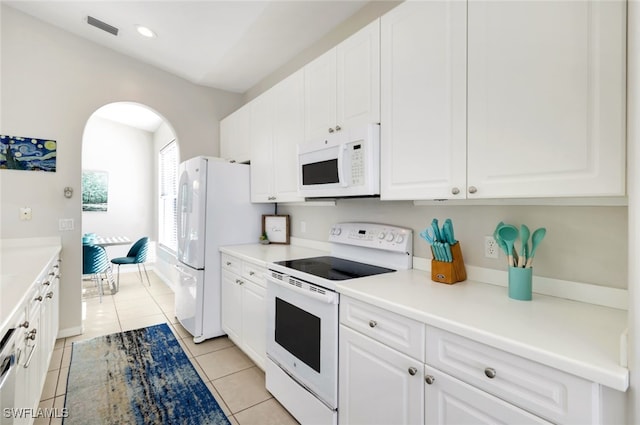 kitchen with light tile patterned flooring, white cabinets, and white appliances