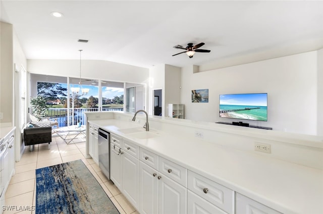 kitchen with light tile patterned flooring, decorative light fixtures, vaulted ceiling, stainless steel dishwasher, and white cabinets