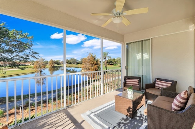 sunroom featuring ceiling fan and a water view