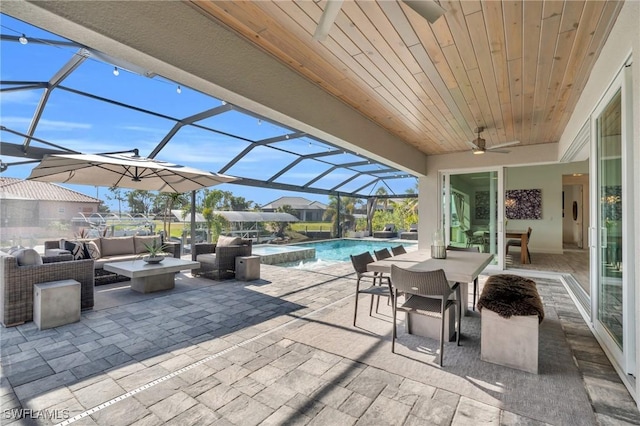 view of patio featuring ceiling fan, outdoor lounge area, and glass enclosure