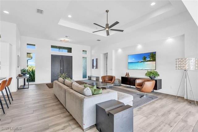 living room with a raised ceiling and ceiling fan