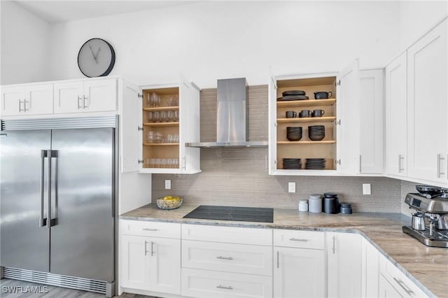 kitchen featuring stainless steel built in refrigerator, white cabinets, black electric cooktop, and wall chimney exhaust hood