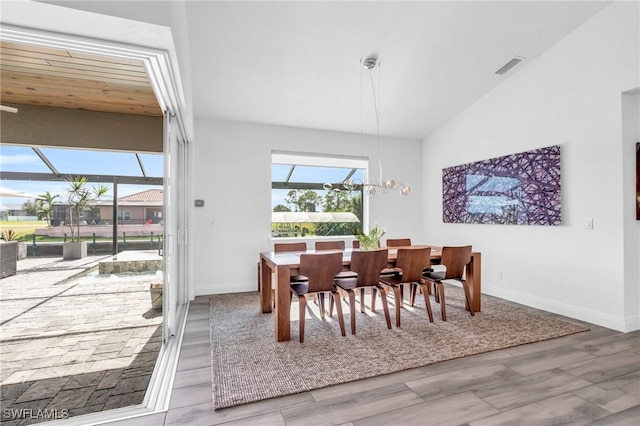 dining space with an inviting chandelier, wood-type flooring, and lofted ceiling