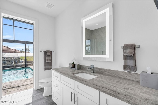 bathroom featuring vanity, toilet, and a shower with door