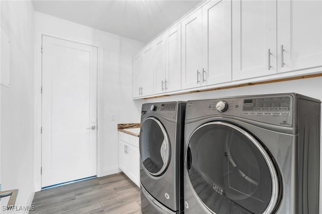 washroom featuring cabinets, independent washer and dryer, and light wood-type flooring