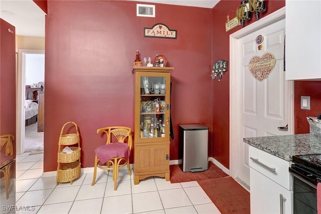 kitchen with white cabinets, light tile patterned floors, and stone counters