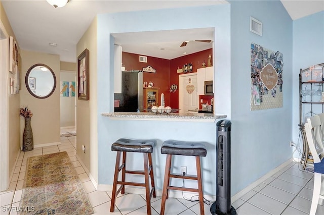 kitchen featuring a breakfast bar, white cabinetry, stainless steel appliances, and light tile patterned flooring