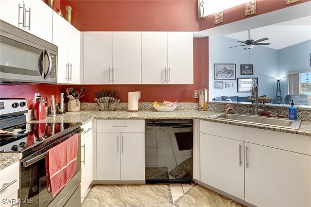 kitchen with appliances with stainless steel finishes, white cabinetry, light stone counters, and sink