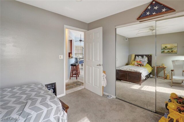 bedroom featuring ceiling fan, light colored carpet, and a closet