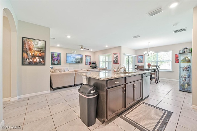 kitchen featuring a kitchen island with sink, dark brown cabinetry, sink, stainless steel dishwasher, and ceiling fan with notable chandelier