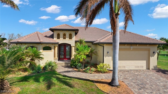 mediterranean / spanish home with french doors, a front yard, and a garage