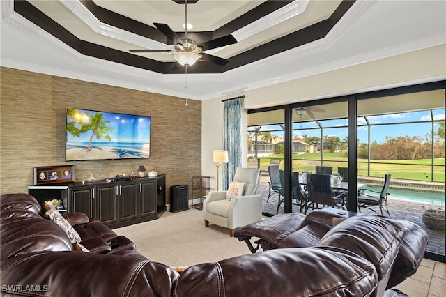 living room featuring light tile patterned flooring, ceiling fan, a tray ceiling, and crown molding