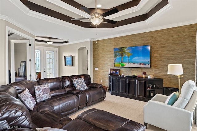 living room with a raised ceiling, light tile patterned flooring, ornamental molding, and ceiling fan