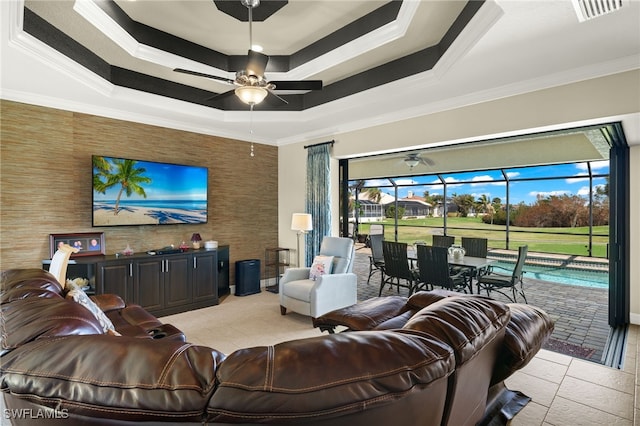 living room featuring a raised ceiling, ceiling fan, a wealth of natural light, and crown molding