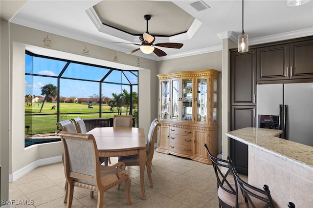 dining space featuring ceiling fan, light tile patterned flooring, ornamental molding, and a tray ceiling