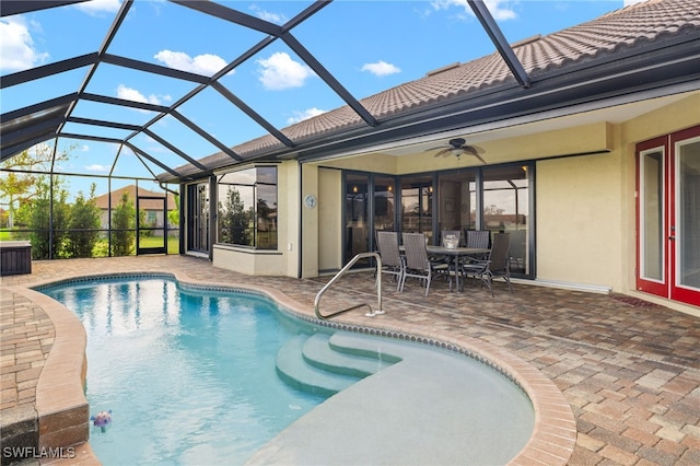 view of pool with ceiling fan, glass enclosure, and a patio