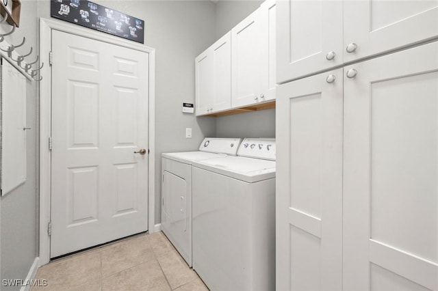 clothes washing area featuring cabinets, light tile patterned floors, and washing machine and clothes dryer