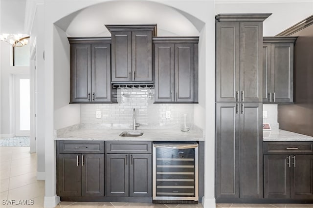 bar featuring sink, decorative backsplash, beverage cooler, and light stone counters