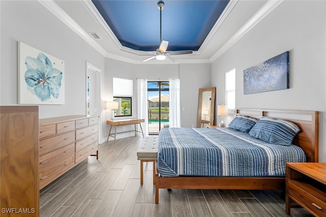 bedroom with access to outside, ceiling fan, a tray ceiling, and crown molding