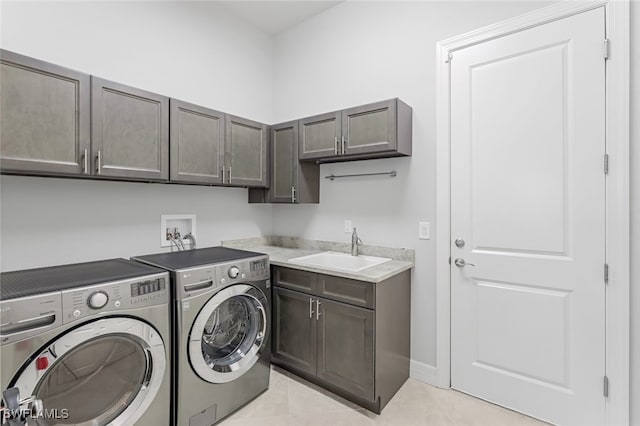 clothes washing area featuring sink, cabinets, washing machine and clothes dryer, and light tile patterned floors