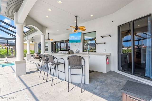 view of patio / terrace with a bar, ceiling fan, and glass enclosure