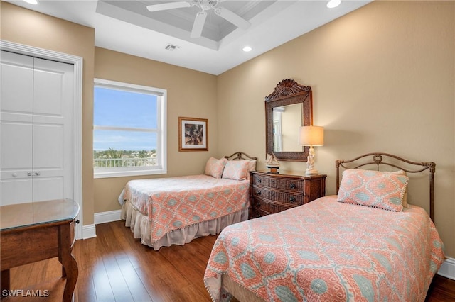 bedroom featuring a closet, ceiling fan, hardwood / wood-style flooring, and a tray ceiling