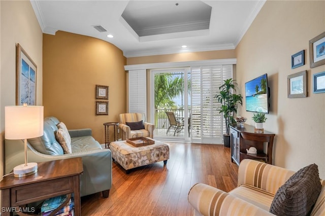 sitting room with ornamental molding, a tray ceiling, and hardwood / wood-style floors