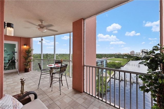 balcony with ceiling fan and a water view