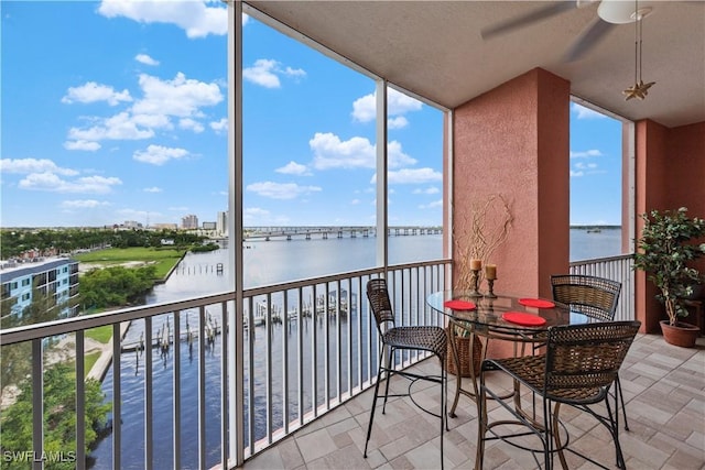 balcony with ceiling fan and a water view