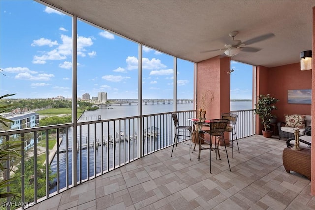 sunroom / solarium with ceiling fan and a water view