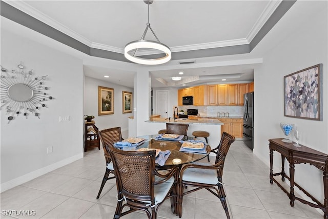 dining area featuring sink, crown molding, a raised ceiling, and light tile patterned floors