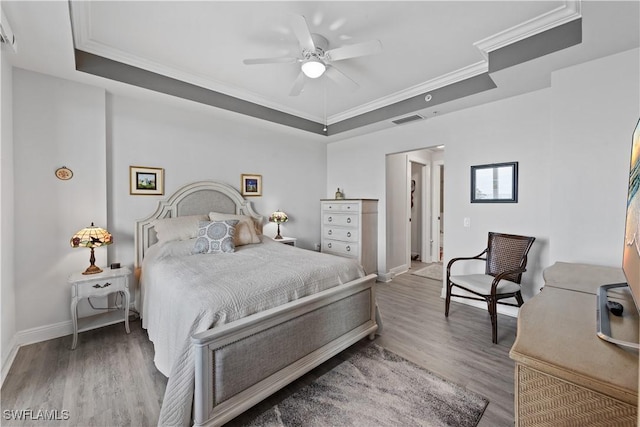 bedroom featuring ornamental molding, ceiling fan, a tray ceiling, and wood-type flooring