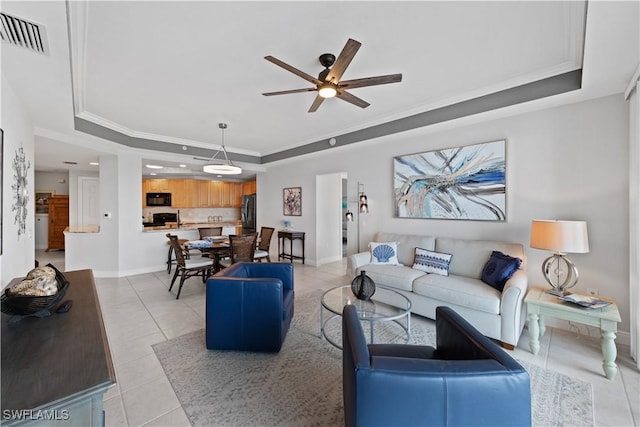 living room with light tile patterned flooring, crown molding, and a tray ceiling