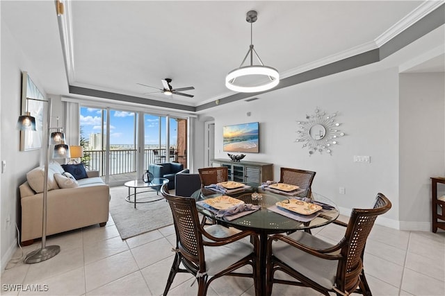 tiled dining area featuring ceiling fan, ornamental molding, and a raised ceiling