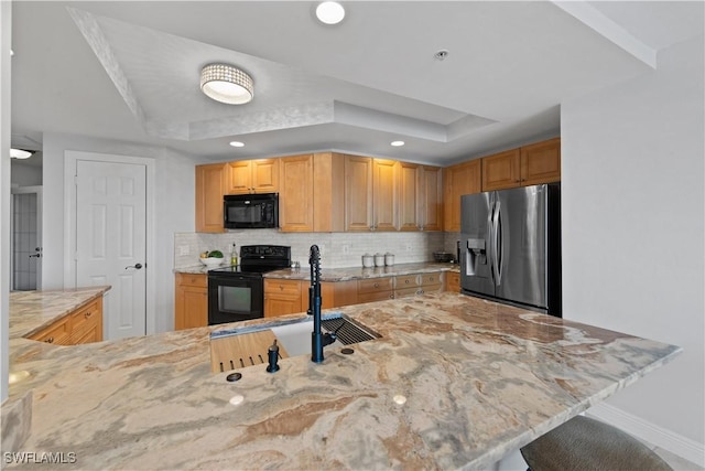 kitchen featuring kitchen peninsula, a tray ceiling, and black appliances