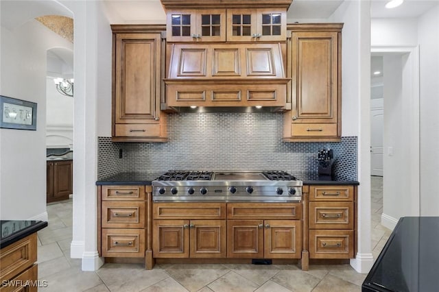 kitchen featuring extractor fan, stainless steel gas cooktop, backsplash, and light tile patterned floors