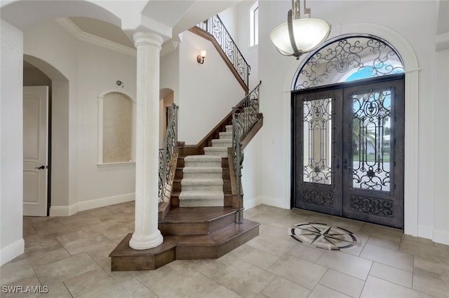 entryway with a towering ceiling, french doors, and crown molding