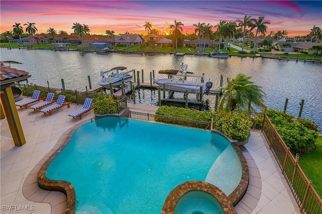 pool at dusk with a boat dock, a water view, and a patio area