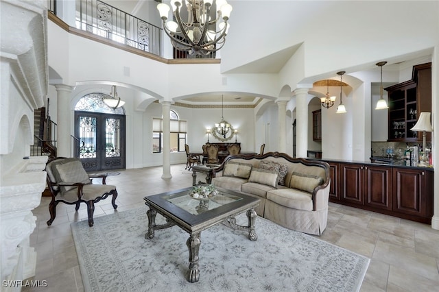 living room featuring a towering ceiling, french doors, and ornate columns